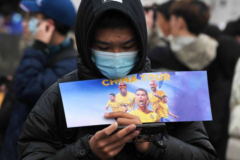 مشجع صيني يحمل تذكرة المباراة الملغية   (أ ف ب)