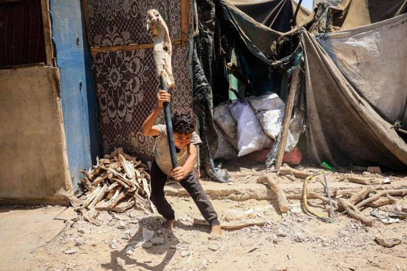 صبي فلسطيني يستخدم قضيباً معدنياً لكسر الحطب في دير البلح أمس (أ ف ب)
