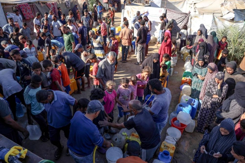 نازحون فلسطينيون ينتظرون الحصول على المياه في ديرالبلح (أ ف ب)