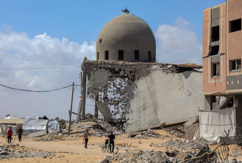 فلسطينيون يسيرون قرب مسجد دمرته غارات إسرائيلية على خان يونس (شينخوا) 