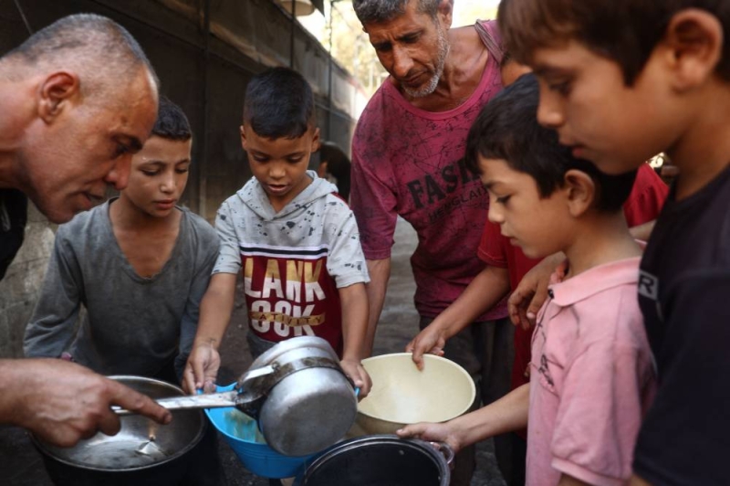 أطفال نازحون ينتظرون الحصول على طعام في ديرالبلح وسط غزة أمس (أ ف ب)